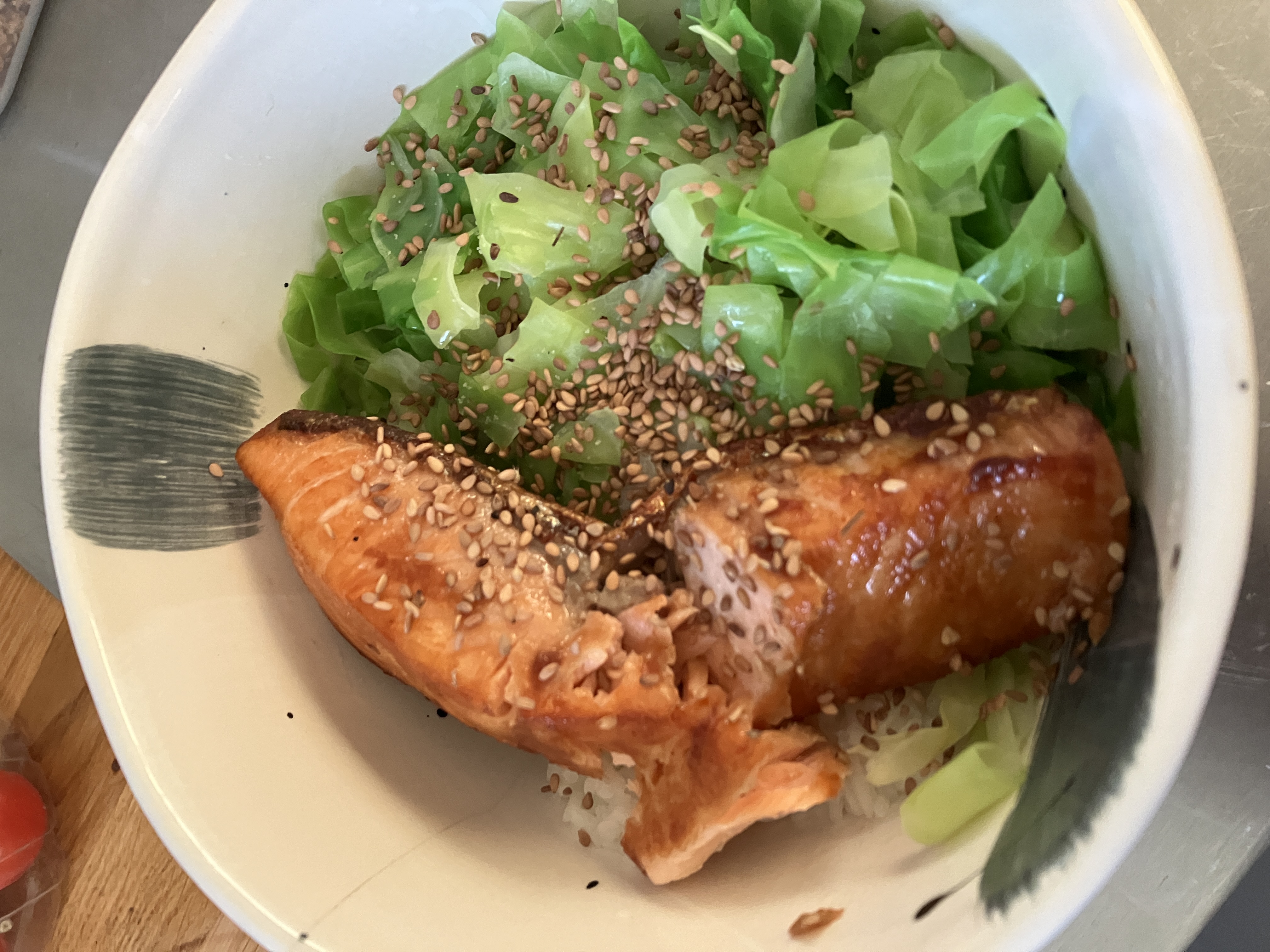 fried salmon and steamed cabbage over rice in a bowl, there are sesame seeds sprinkled on top